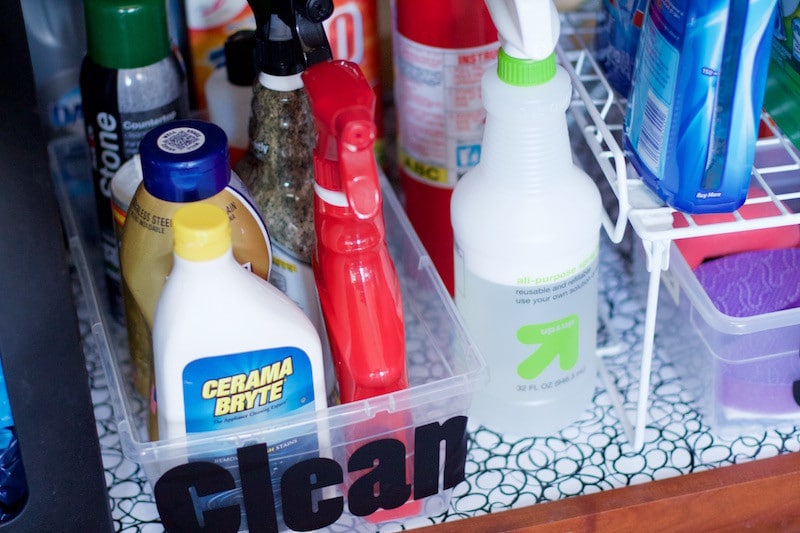 Under sink storage with cleaning supplies in clear showbox without the lid and a label that says clean, along with shelf riser to hold other supplies #miscellaneous #konmari