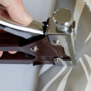 Hand using a staple gun to upholster a chair seat. #upholster