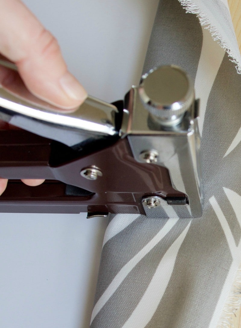 Hand using a staple gun to upholster a chair seat. #upholster