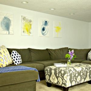 Green couch with pretty pillows and pictures to represent the Completed Basement #basement