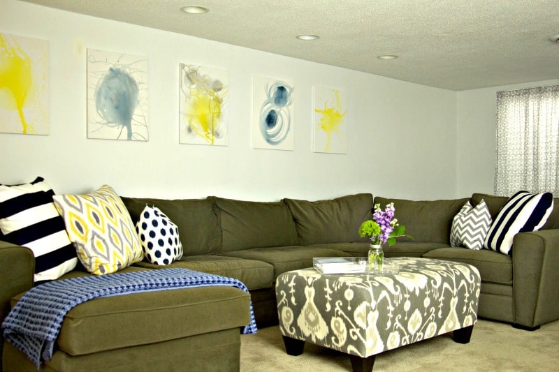 Green couch with pretty pillows and pictures to represent the Completed Basement #basement