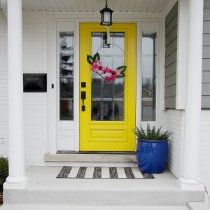 yellow front door with faux flower hoop wreath. Using items found from the Dollar Store, you can create a faux flower hoop wreath in this easy-to-follow tutorial with lots of pictures to help you create this spring trend! #fauxflowers #dollarstore #hoopwreath