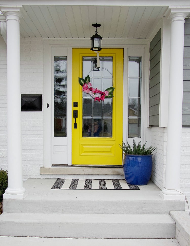 yellow front door with faux flower hoop wreath. Using items found from the Dollar Store, you can create a faux flower hoop wreath in this easy-to-follow tutorial with lots of pictures to help you create this spring trend! #fauxflowers #dollarstore #hoopwreath