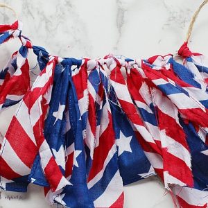 This easy no-sew tutorial shares how you can create a DIY Patriotic Bunting using bandanas and twine from the Dollar Store. #patriotic #fabricbunting