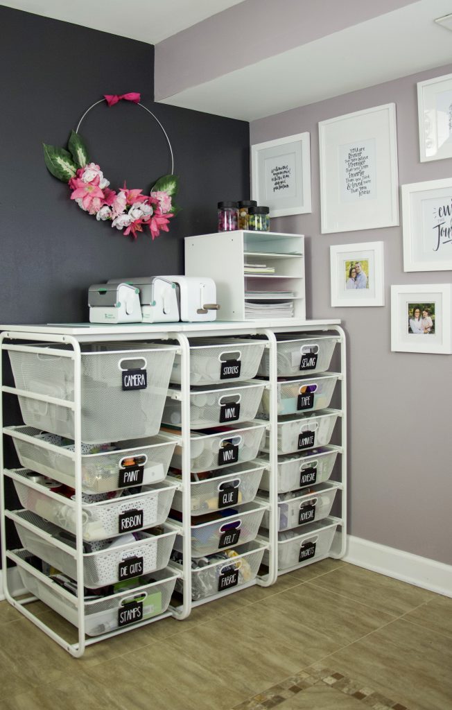 Organize your home offiec with Elfa drawers and labels on each drawer. Categorize each drawer and label so you know what is inside. Elfa system against black wall and purple wall with wall art to create a beautiful and organized space #organized #craftorganization
