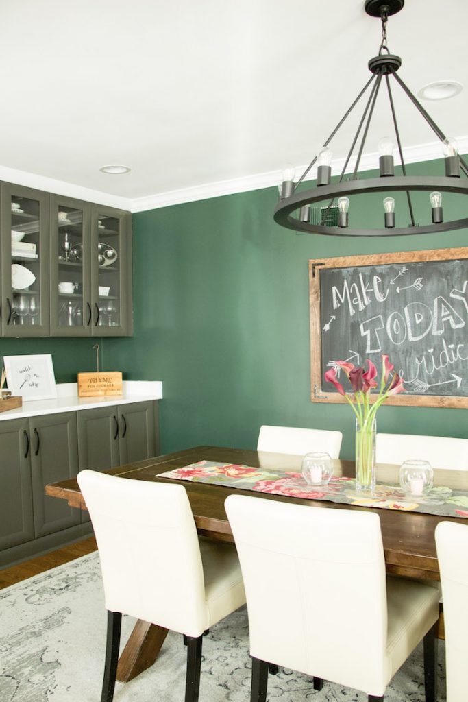 Dining area in open concept kitchen with dark hunter green paint against grey cabinets and wooden accents #kitchendecor #diningroom #darkpaint