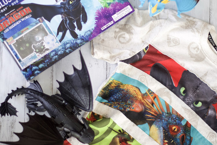 Flatlay of How To Train Your Dragon 3 movie box set with action figure dragons and t-shirt