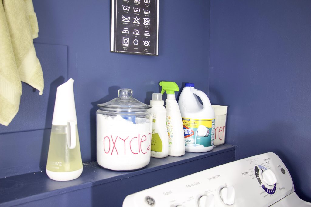 shelf with laundry detergents and glass jars to showcase how to create laundry room storage in a small laundry room