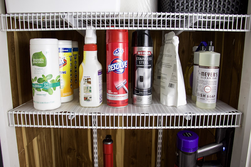 Wire shelving with clear easyliner on top and cleaning supplies lined up for drawer organization