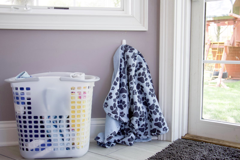 tote with rolled beach towels next to back door to demonstrate towel storage ideas #towelstorage