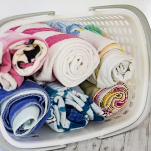 Beach towels rolled up in a basket to represent how to get organized for summer #summer