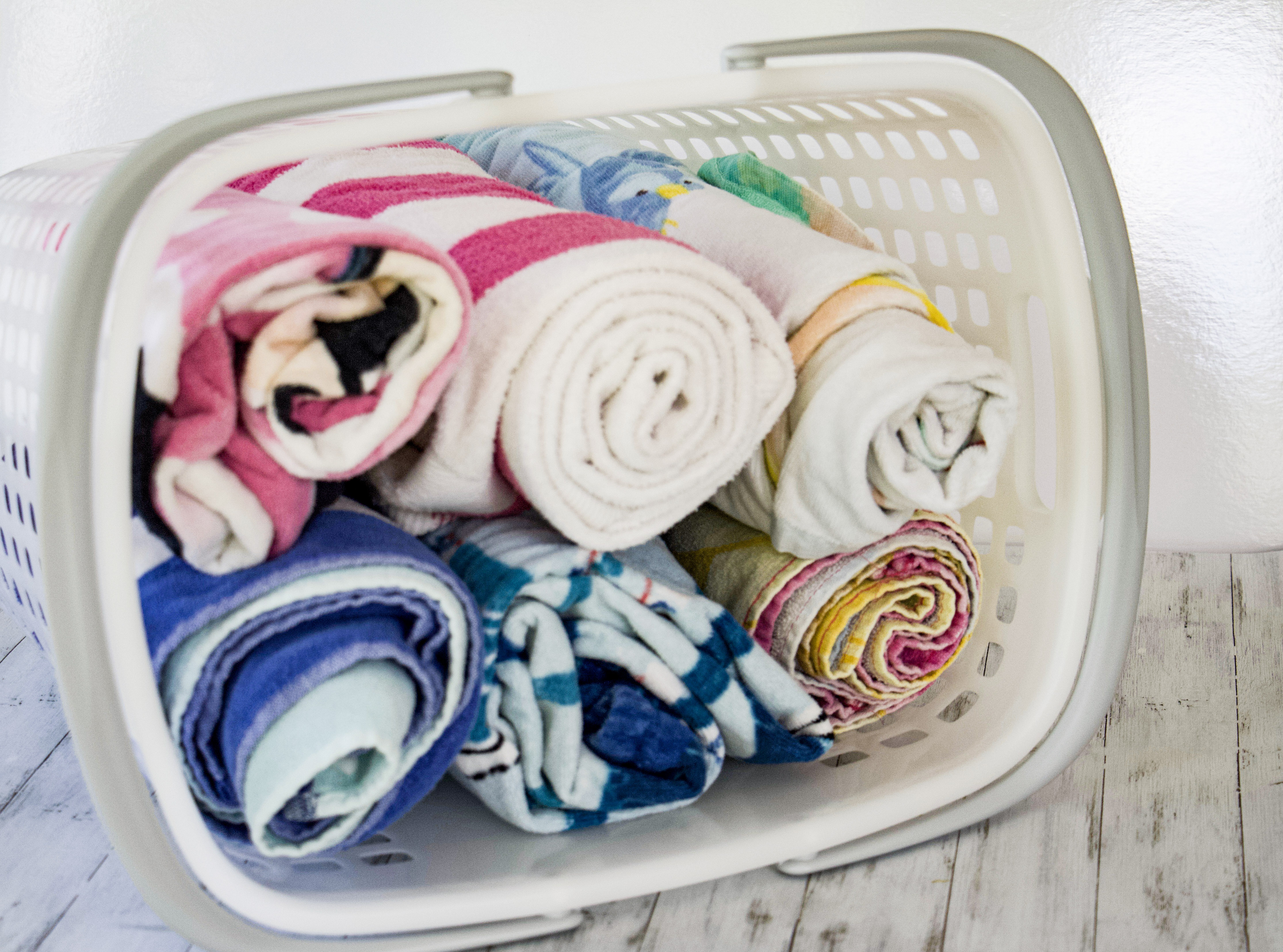 Beach towels rolled up in a basket to represent how to get organized for summer #summer