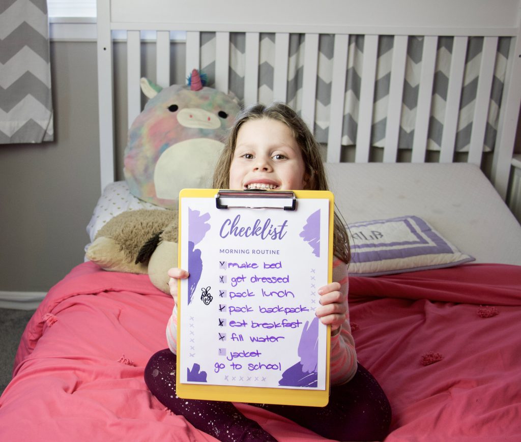 Child holding morning routine checklist on a clipboard #morningroutine #routinesforkids