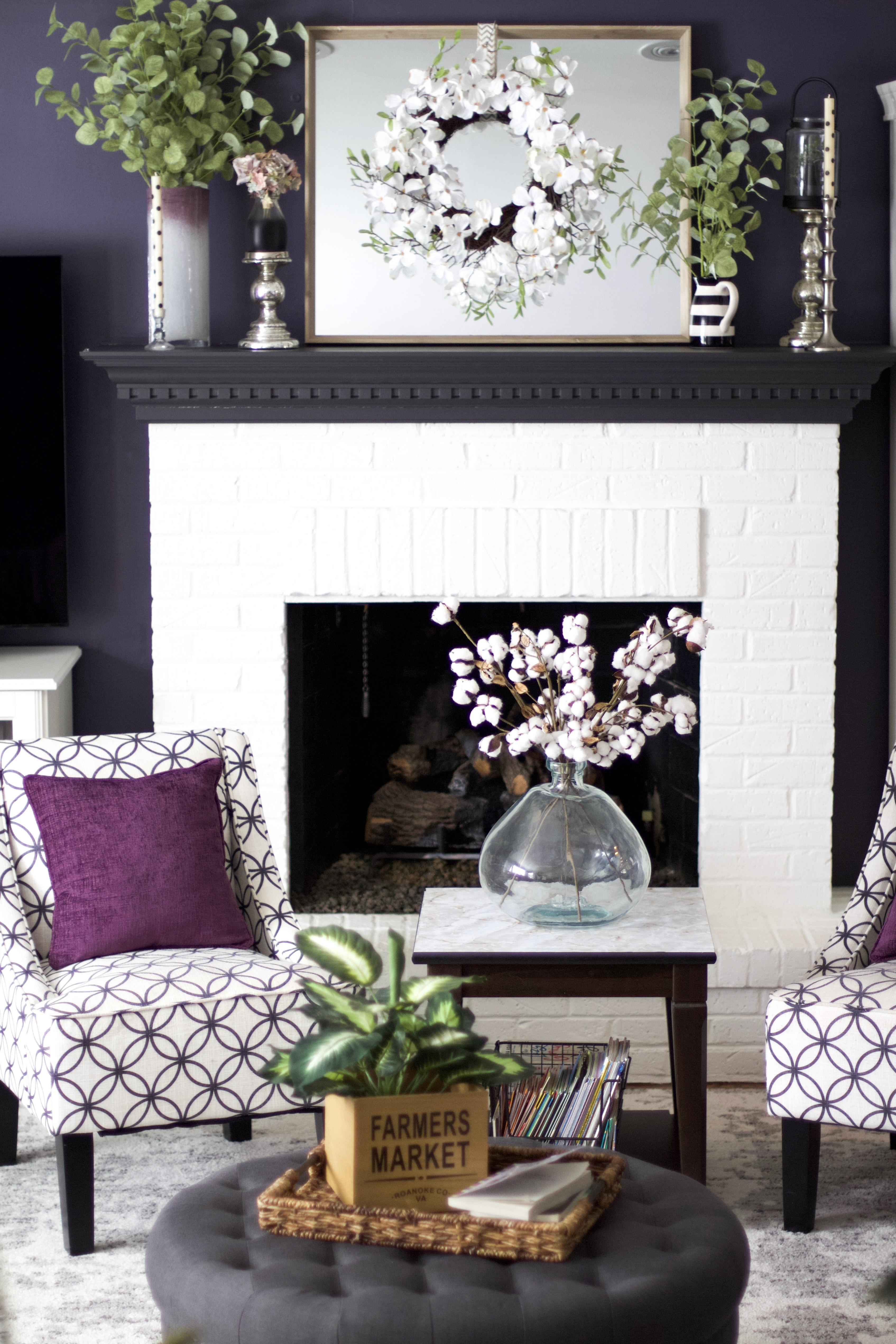 living room with white fireplace and grey mantel with mirror and wreath on mantel