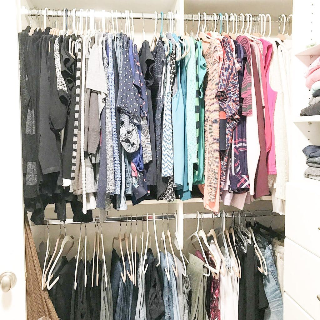 closet organized by color with shirts on top and pants on bottom