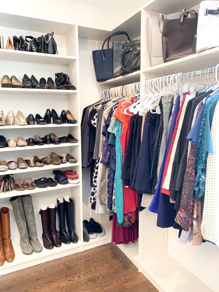closet with shoes on shelves and dressed color coordinated