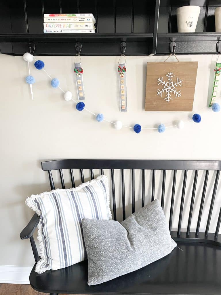 close up of bench with blue and white pillows and garland hanging from shelving above bench