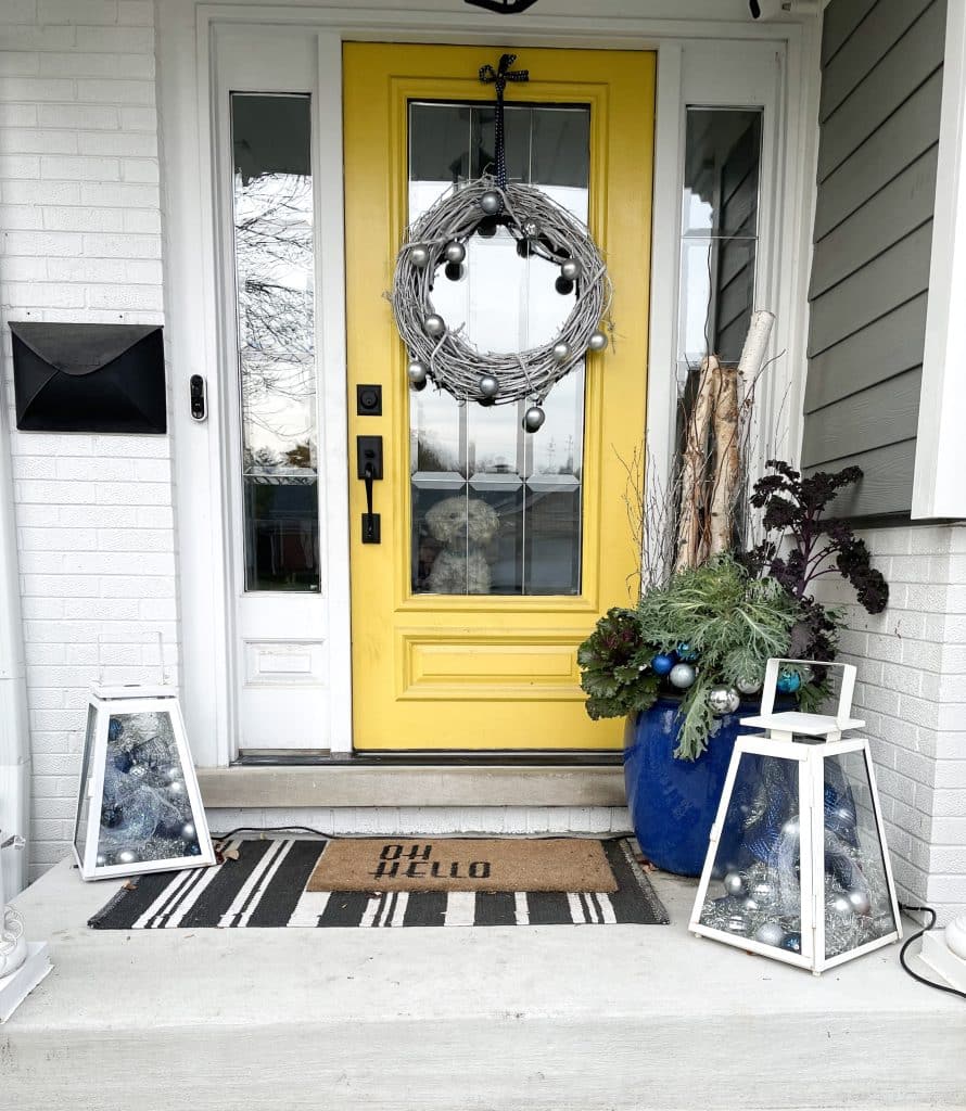 yellow front door with blue and silver decor in lanterns