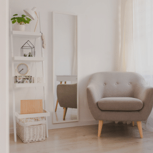 white shelf next to light grey chair and mirror