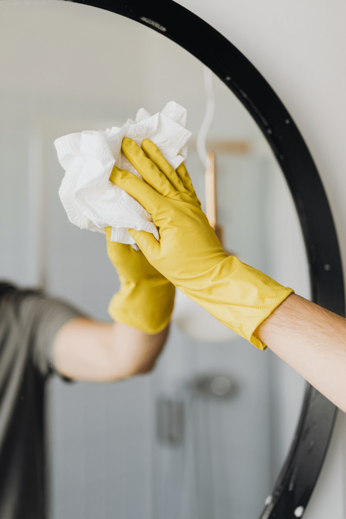 cleaning mirror with gloves and rag