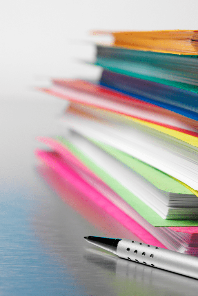 colorful piles of paper with a pen